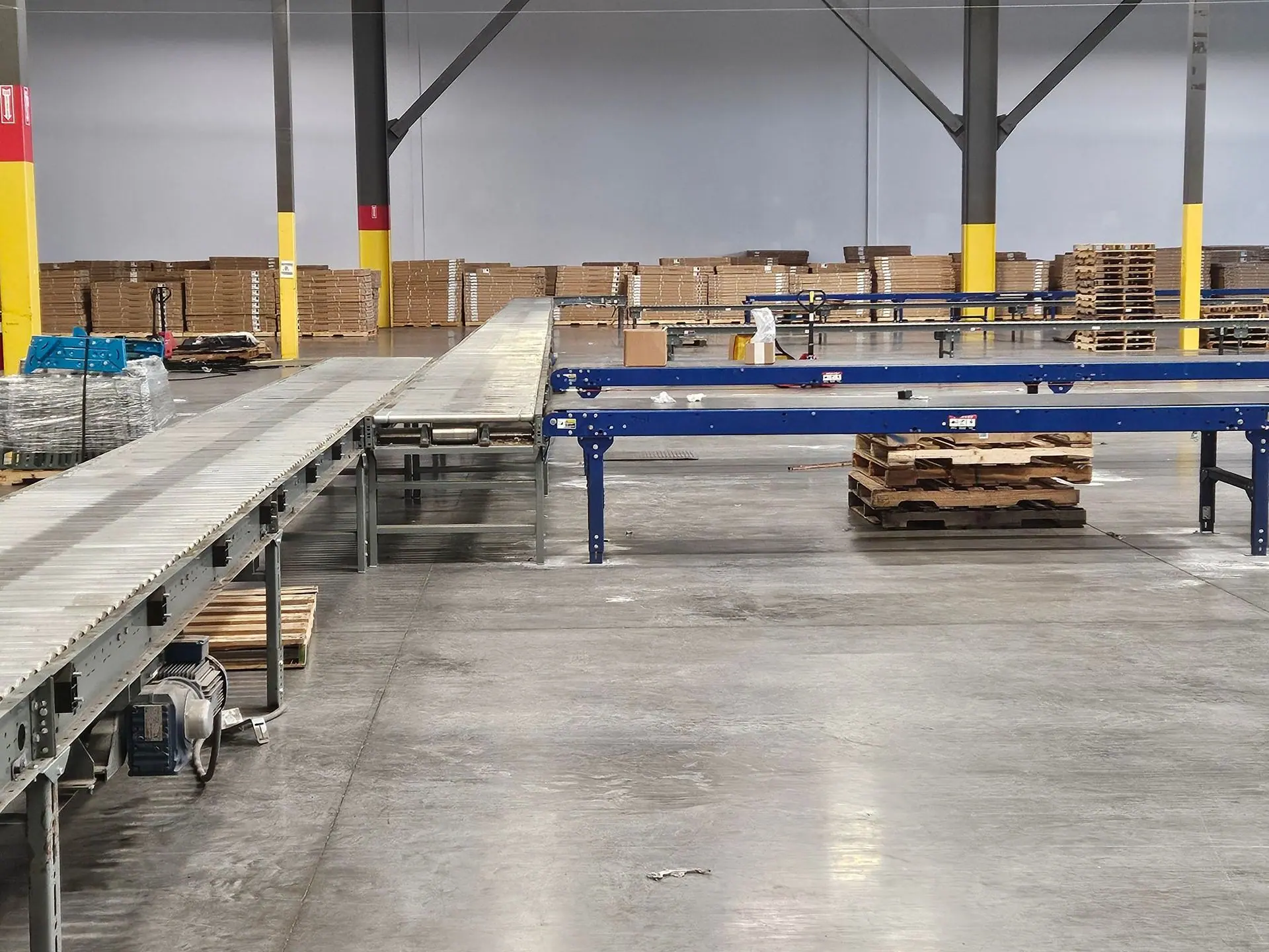 Roller and belt conveyor lines installed across an empty warehouse floor